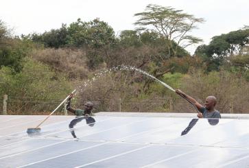 Two men clean solar panels in Kenya