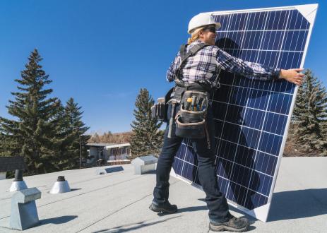 Women holding solar panel on roof
