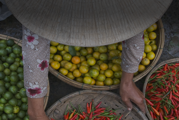 Women holding woven baskets with fresh vegetables and fruit 